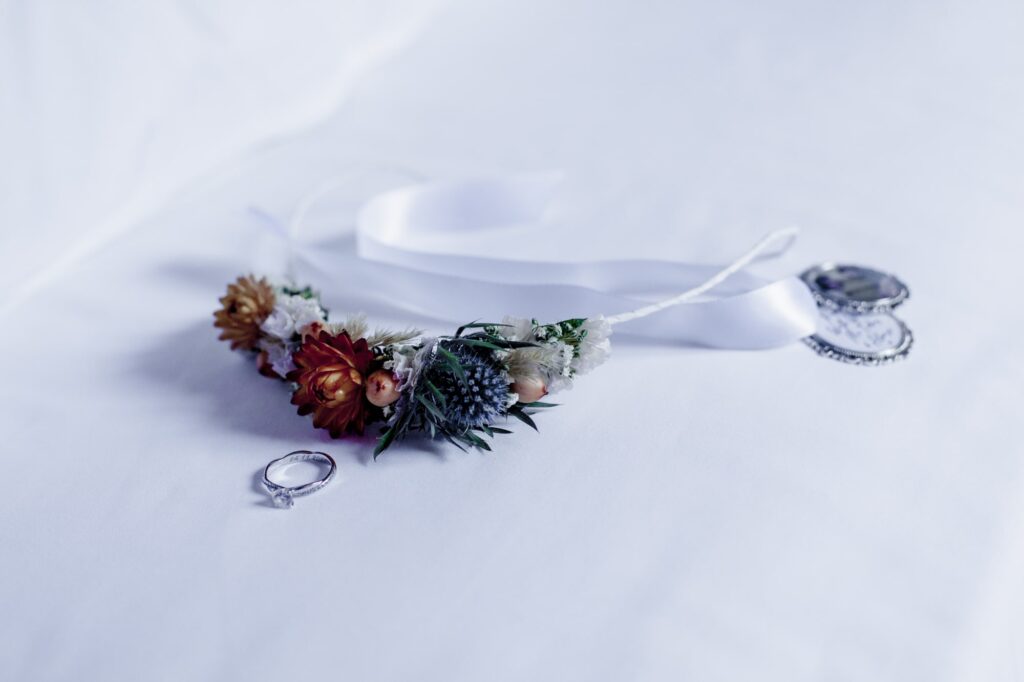 Hochzeitsfotograf Brandenburg Brauthaar Deko auf Blumen und Brautring auf weissem Laken