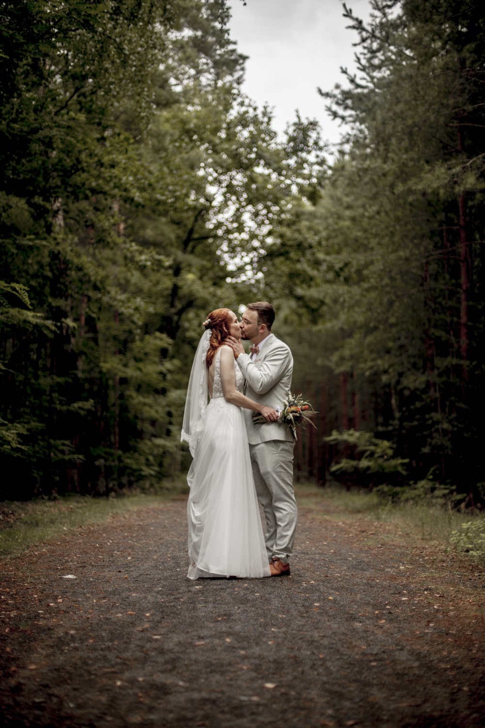 Hochzeitsfotograf Peitz Brautpaarshooting das Brautpaar küsst sich in einer Lichtung in einem dichten Wald