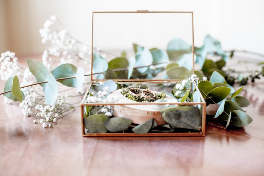 Hochzeitsfotograf Potsdam gläserne Trauringbox mit Goldrand gefüllt mit Eukalyptus und goldenen Trauringen