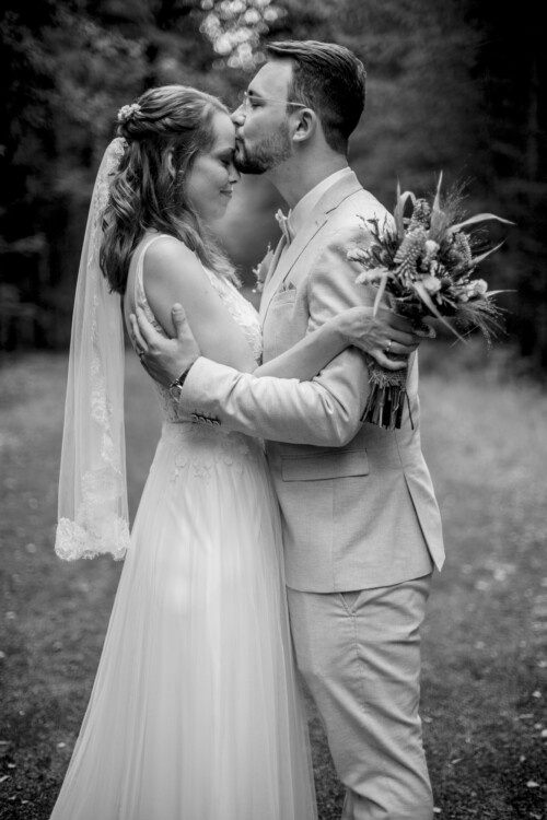 Hochzeitsfotograf Berlin Bräutigam küsst Braut auf Stirn im Wald in Richtershorn am See